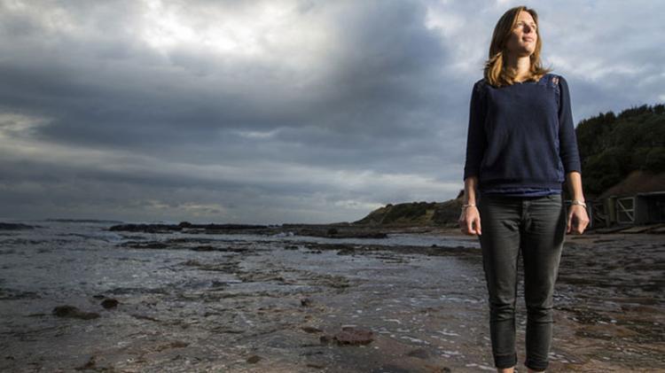 A UOW Geoquest researcher stands on the shores of the ocean
