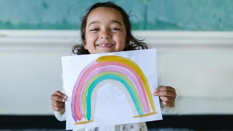 Female child proudly shows rainbow painting