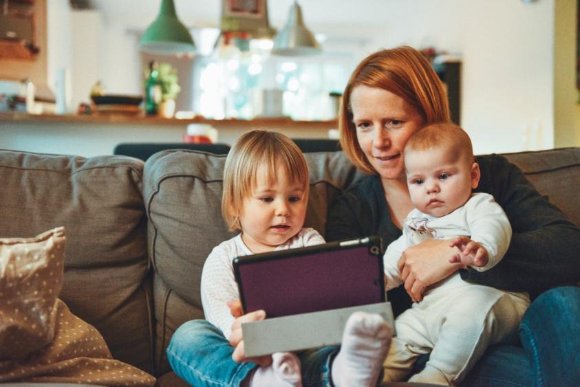 Mother with toddlers sitting on lounge using an iPad
