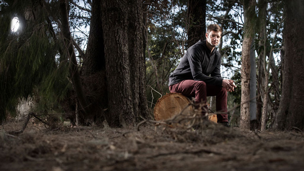 Chris Gordon sitting on a log in the bush
