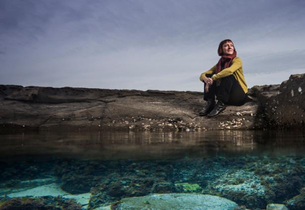 UOW researcher Leah Gibbs sits on rocks near water
