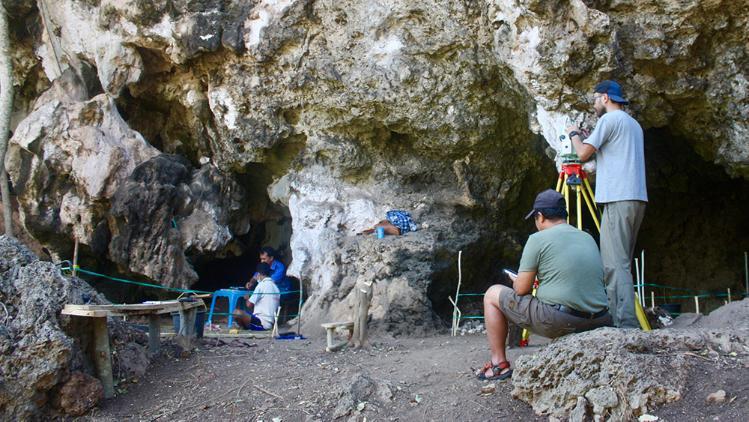 UOW science academics dig through rock samples in a cave in Timor