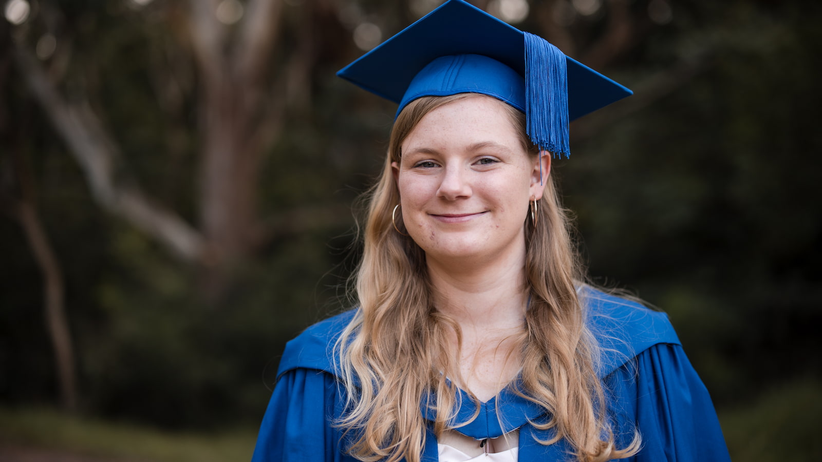 Elizabeth Caine has a smile on her face and wears a graduation gown and cap. Photo: Michael Gray