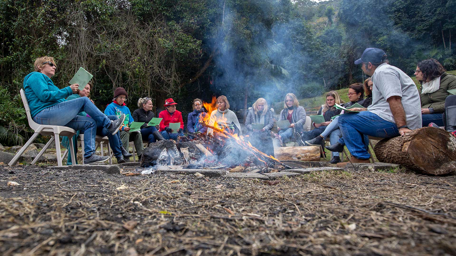 Students and teachers sitting around a fire