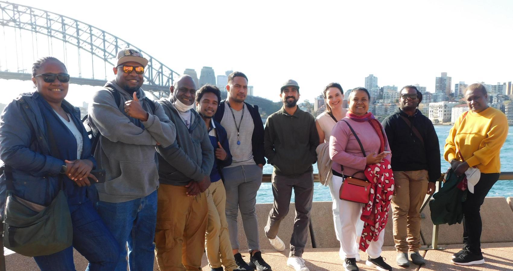 A group of people pose in front of the Harbour Bridge in Sydney