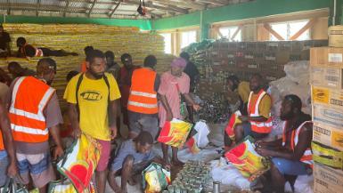 A dozen people working to sort food as part of a cyclone relief effort in Vanuatu