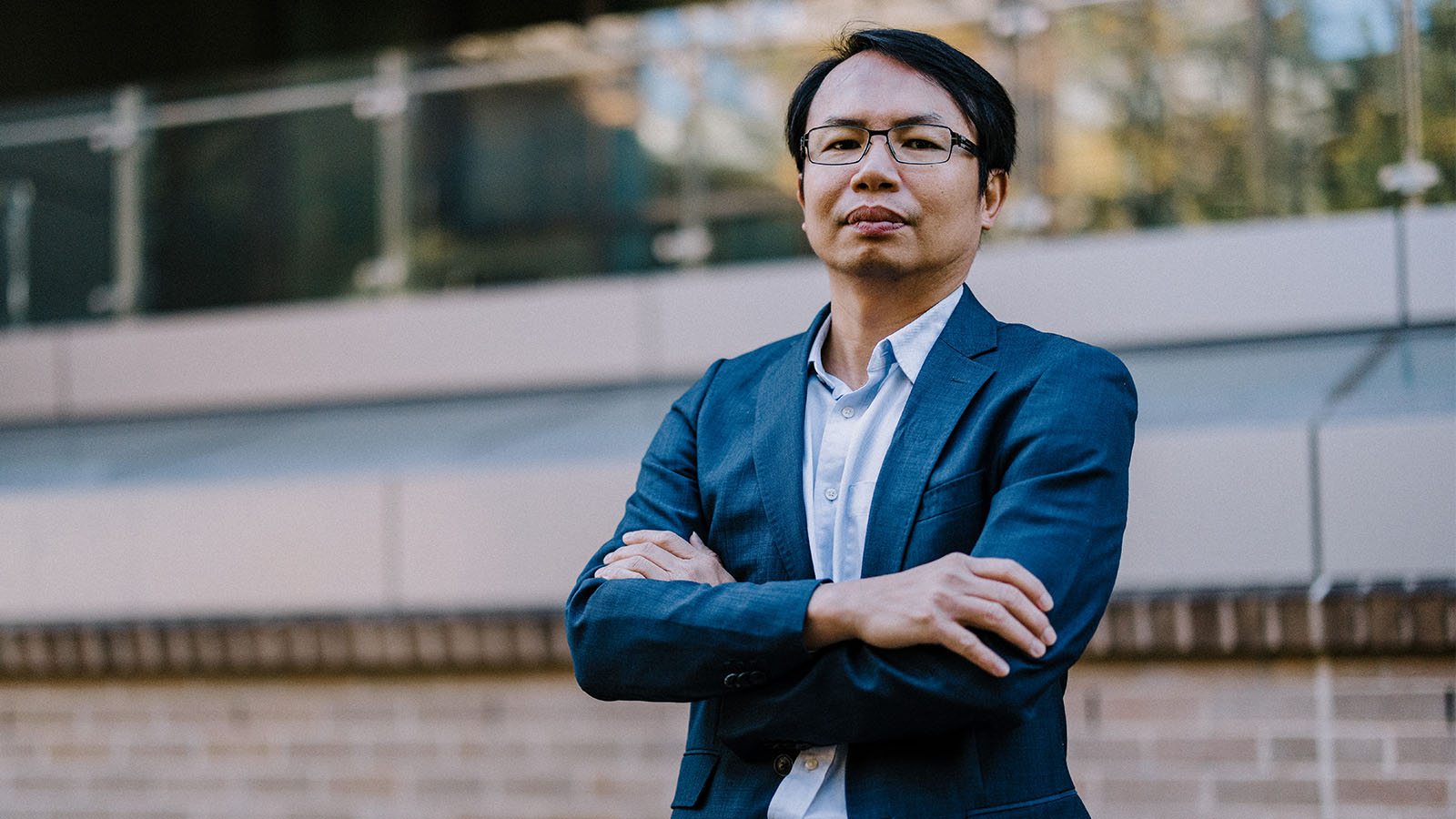 A man standing outside of building with his arms crossed.