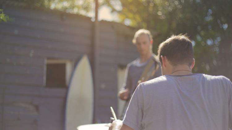 two males outside a home with surf boards