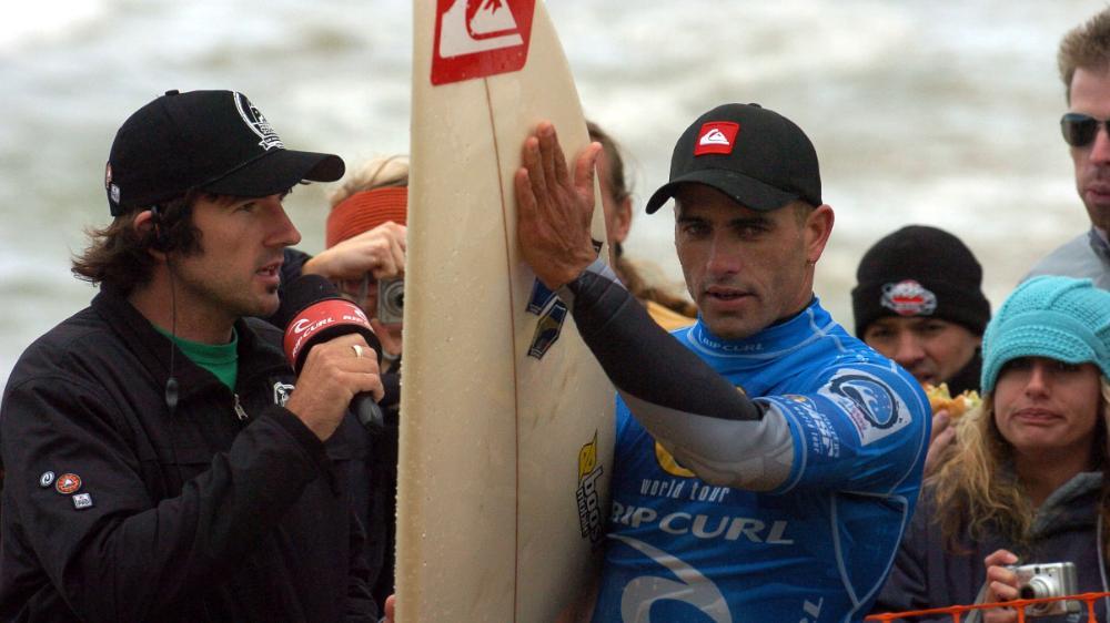 UOW graduate Dane Sharp holding microphone next to surfer Kelly Slater