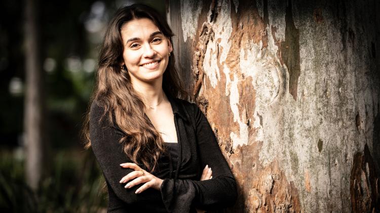 Nicole Russo leaning against a tree smiling