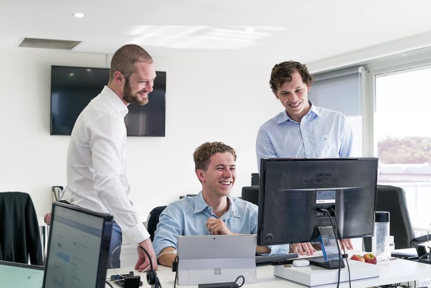 Kieran with two team members at a desk