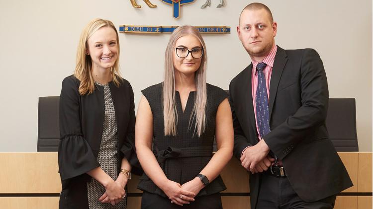 Three law students standing in moot court