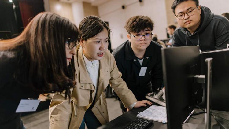 Student demonstrates project to her peers on a desktop computer