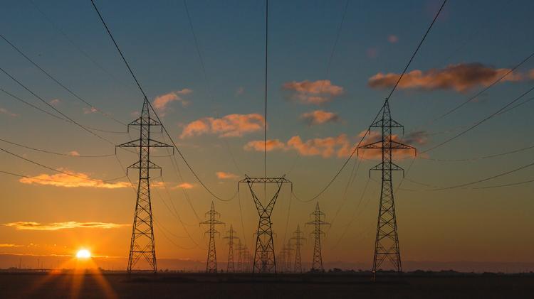 Power grid towers with the sun setting in the background