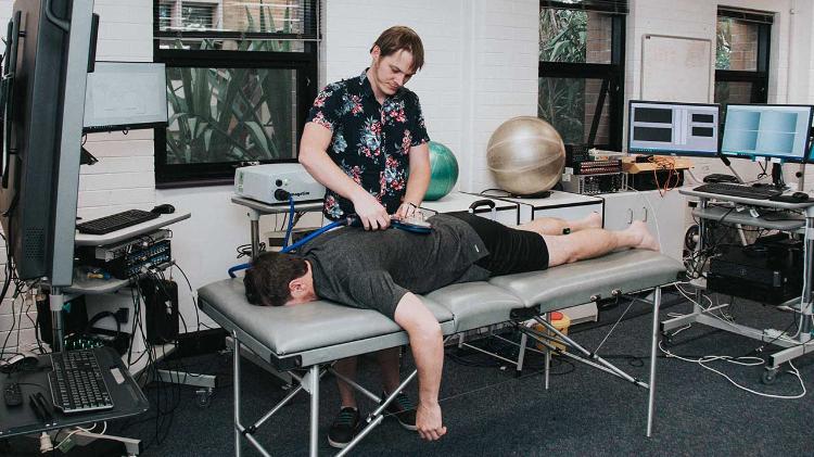 Man laying on massage bed, inducing plasticity in the spinal cord