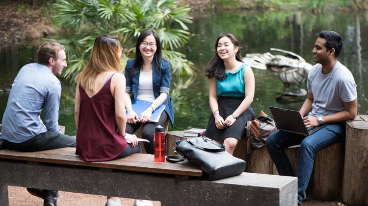 Group of UOW students sitting around Duckpond lawn