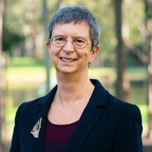 Distinguished Professor Wendy Rogers posing for a headshot with trees and grass behind her