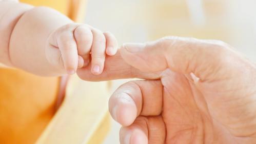 Infant holding hand of an adult