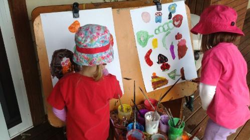 Children painting on easels in a preschool setting