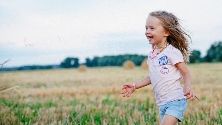 Young girl running, carefree through a field