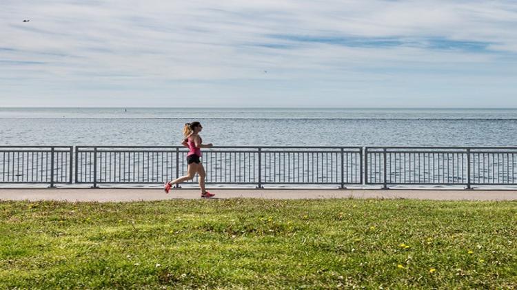 Lady running along boardwalk with ocean in background
