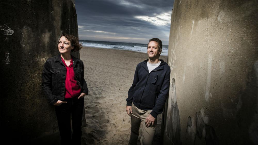 Andrew Warren and Leah Gibbs standing on steps at beach