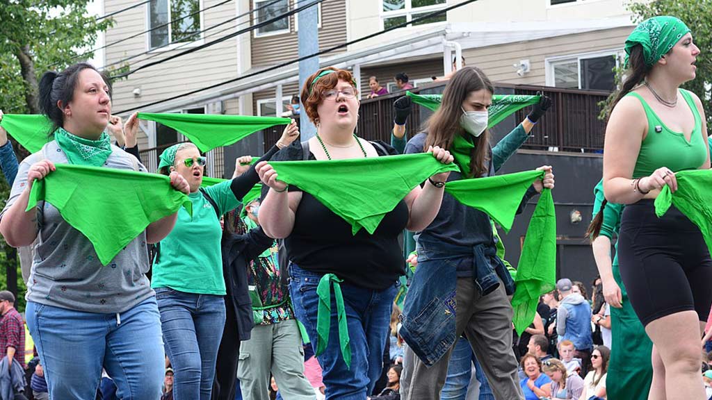 Image from Joe Mabel shared under a creative commons licence. Abortion rights protestors march with green bandanas in their hands at the 2022 Summer Solstice Parade, Fremont, Seattle, Washington.