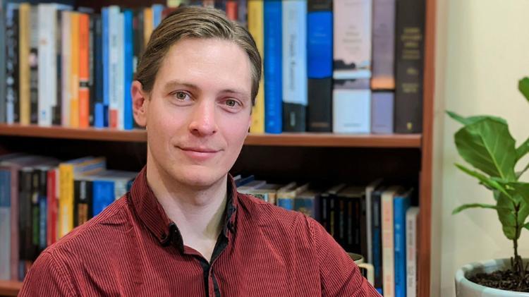 Adam Piovarchy with a bookshelf behind him