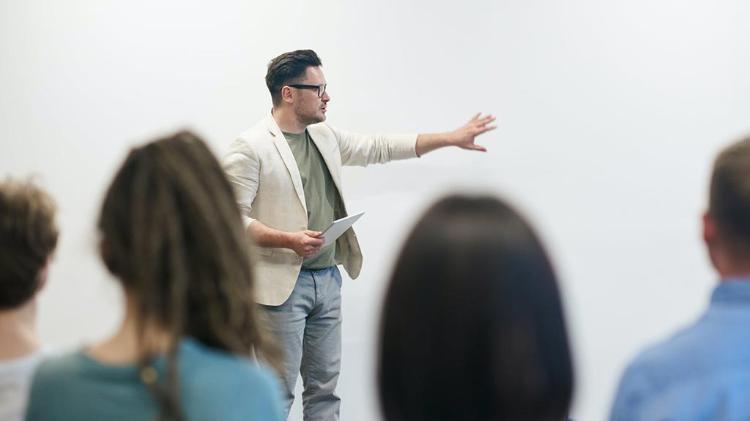 man standing infront of class pointing at whiteboard