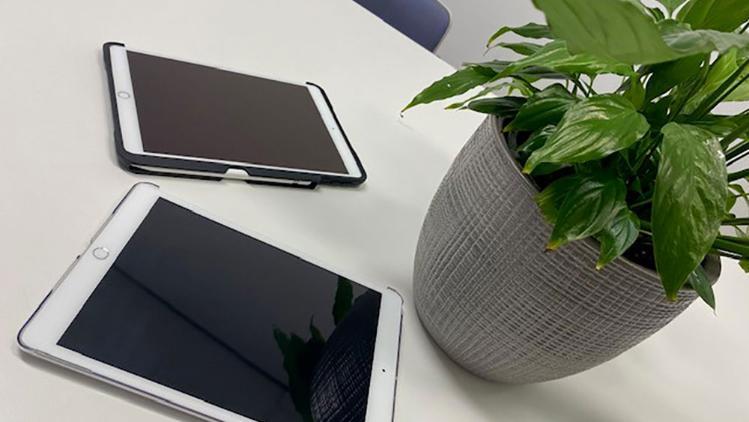 Tablet and Smartphone on a white table with a grey plant pot