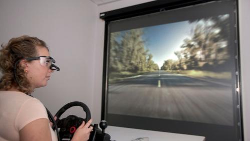 Student sitting in front of screen playing racing game