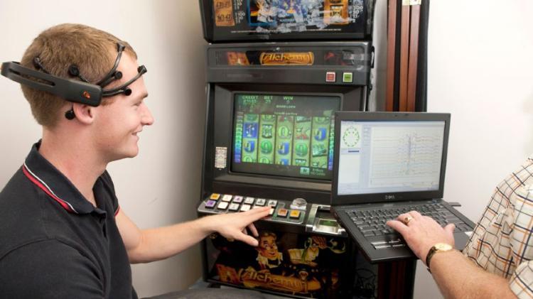 Student hooked up to brain tracker while playing pokie machine