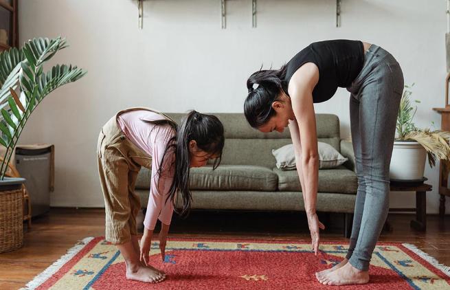 Daughter and mother doing yoga in the lounge room