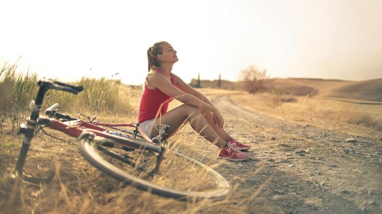 Lady resting on side of road with bike