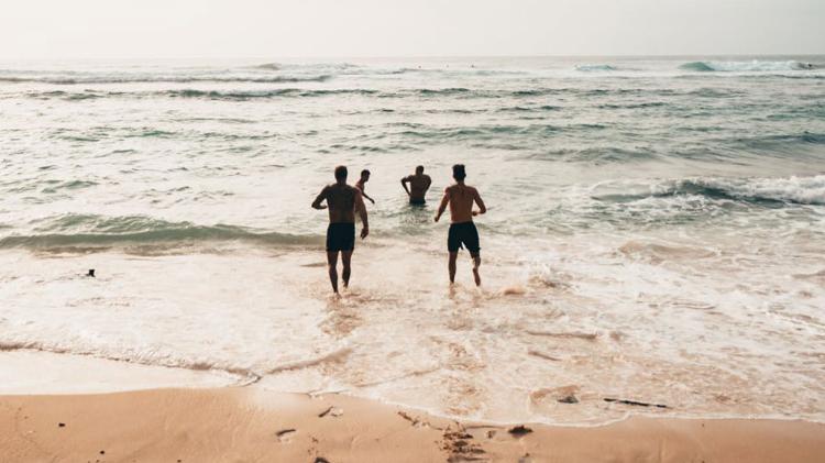 4 men running into the water at the beach