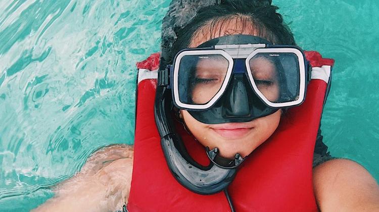 Lady with goggles and snorkle on, laying on back in water