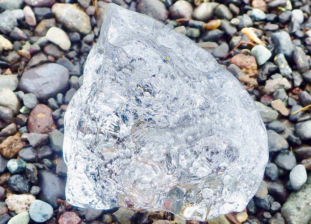 A huge chunk of ice sitting on a pile of pebbles