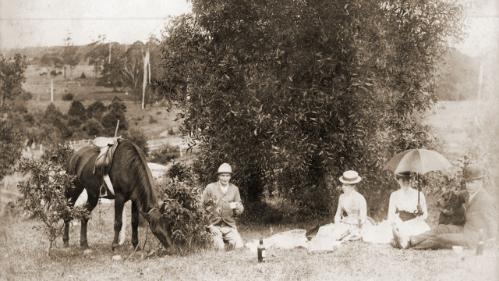 Photograph from the Pringle album of two men and two women with parasols having a picnic. Henry Arthur Pringle laying at left near dog and horse.