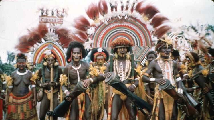 A tribal group with extravagant feathers and drums