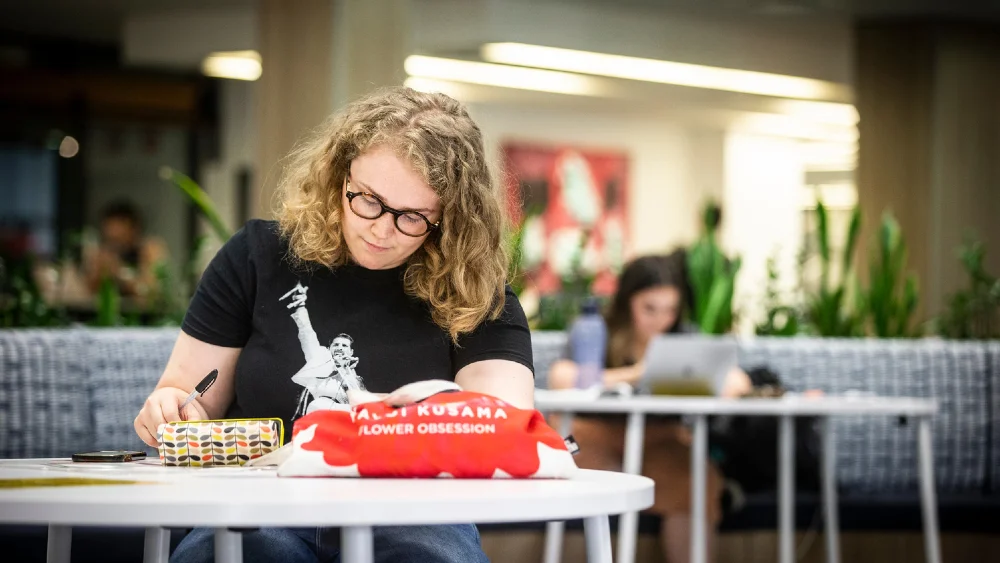 Student sitting at a desk on the ground floor of Wollongong Campus Library