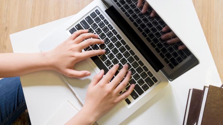 A person's hands typing on a laptop