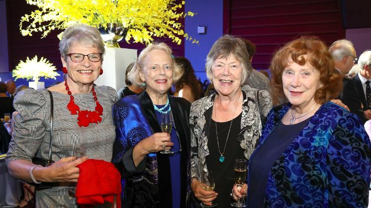 Four women standing smiling at camera at awards night.