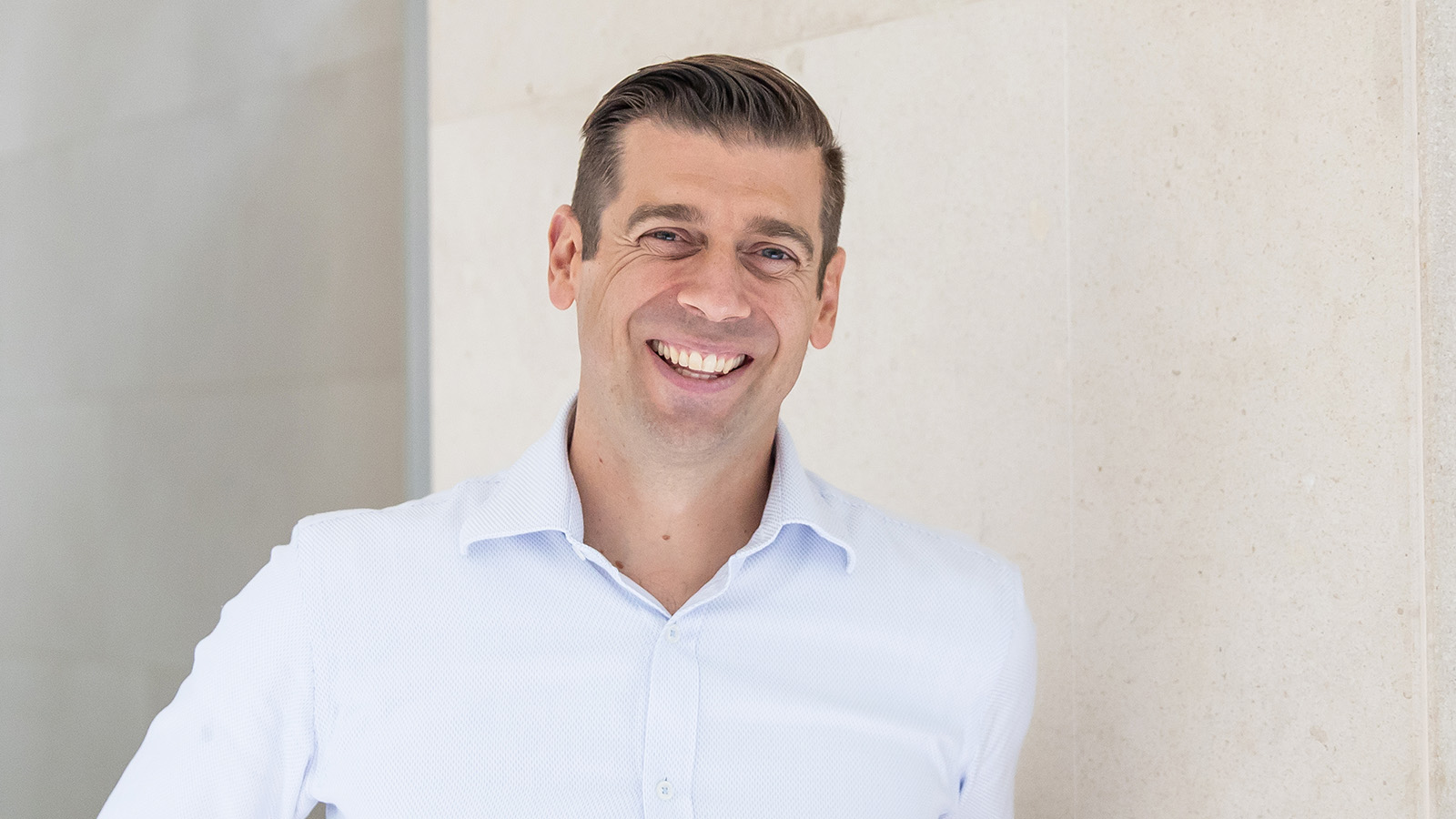 A man is wearing a white business shirt, smiling