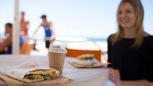 A student eating breakfast and having a coffee at a cafe by the beach.