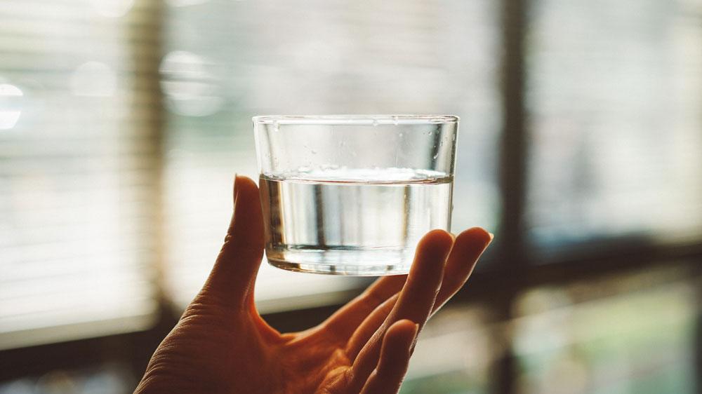 A hand holding up a glass of water.
