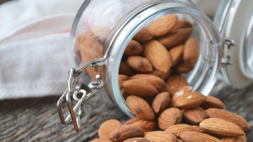 A jar of almonds spilling onto the table.