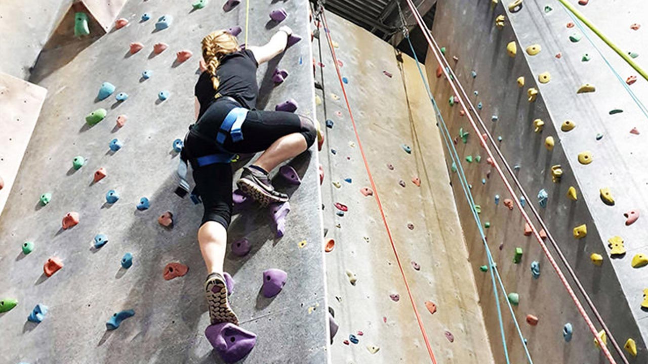 Woman climbing up artificial rock wall