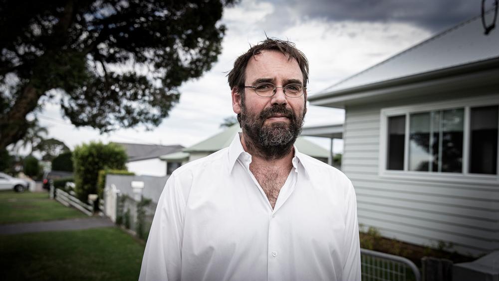 Dr Chris Degeling stands outside in front of a house.