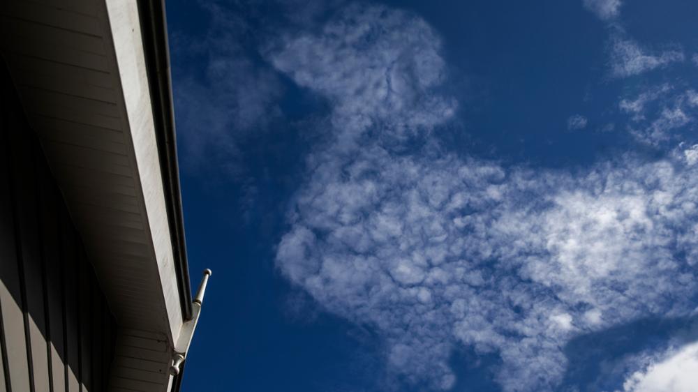 A white speckled cloud shaped like a dachshund in the blue sky.