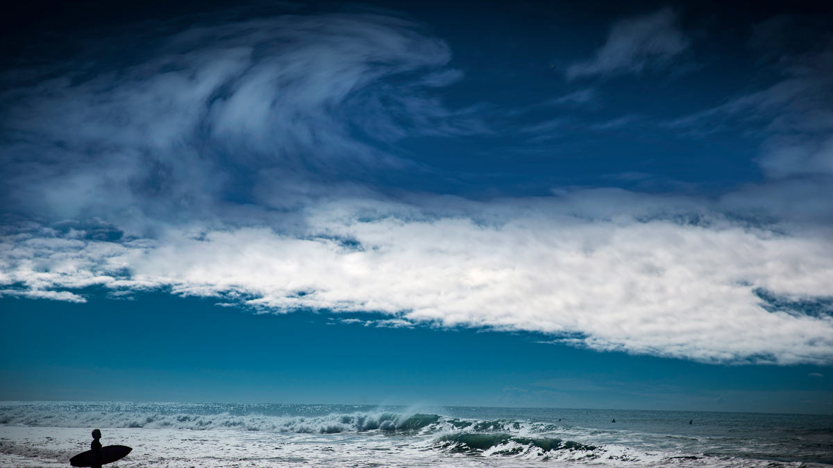 A cloud shaped like a wave above the ocean